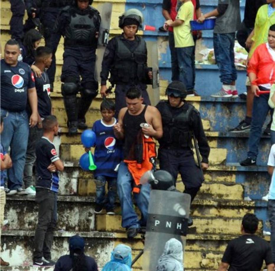 Elementos de la Policía se llevan a un hincha que estaba acompañado por un niño aficionado del Motagua.