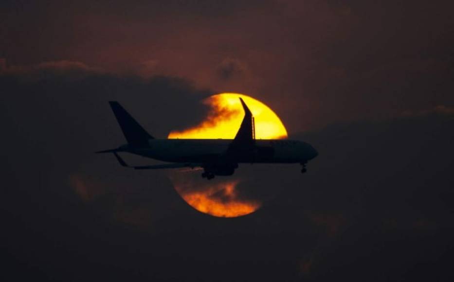 Un avión vuela sobre Bogotá durante la puesta de sol el 19 de marzo de 2020. En esta ciudad se bloqueará todos los vuelos internacionales desde el lunes durante 30 días. Foto AFP