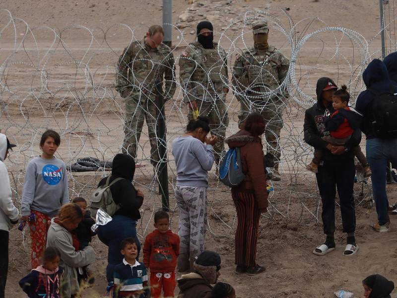 Migrantes intentan cruzar la cerca de alambres en la frontera que divide a México de los Estados Unidos.