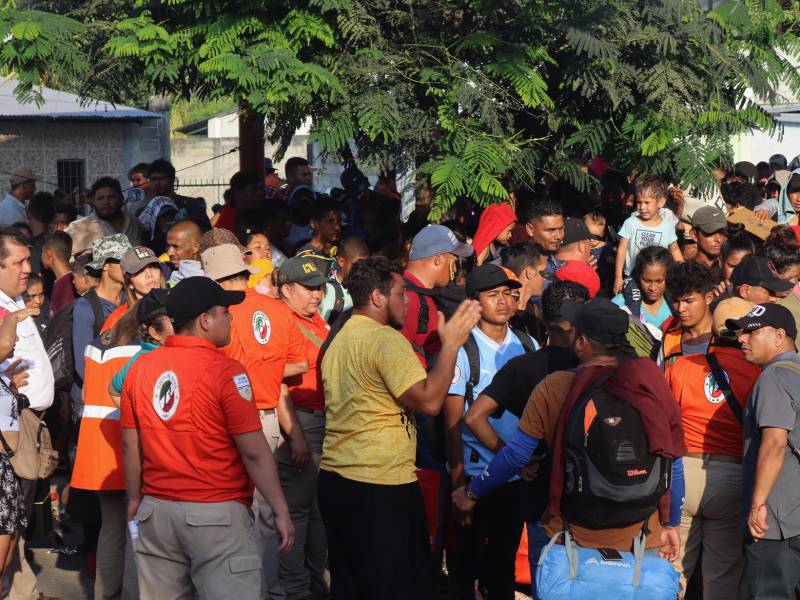 Miembros del Instituto Nacional de Migración (INM) dialogan con migrantes instalados en un campamento improvisado en una cancha deportiva hoy, en el municipio de Mapastepec, estado de Chiapas.