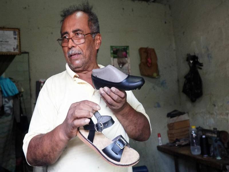 <b>Óscar Gómez muestra el calzado que elabora en la sala de su pequeña vivienda; locales frente a fábrica de Choloma permanecen vacíos. Fotos: José Cantarero y Héctor Edú. </b>