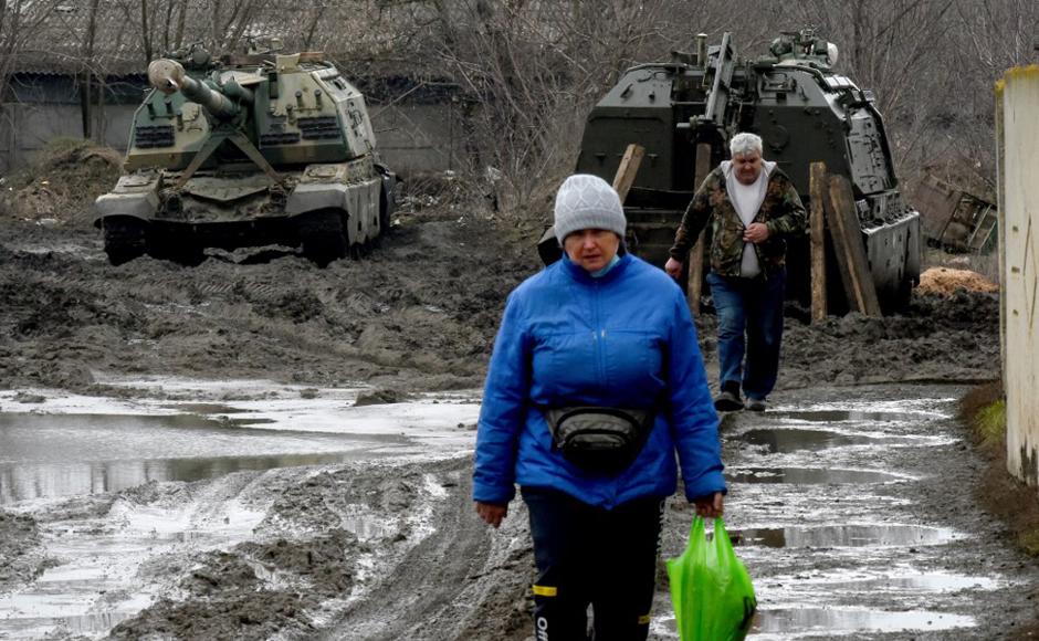 La gente camina frente a vehículos blindados rusos en una estación de tren en la región de Rostov, en el sur de Rusia.