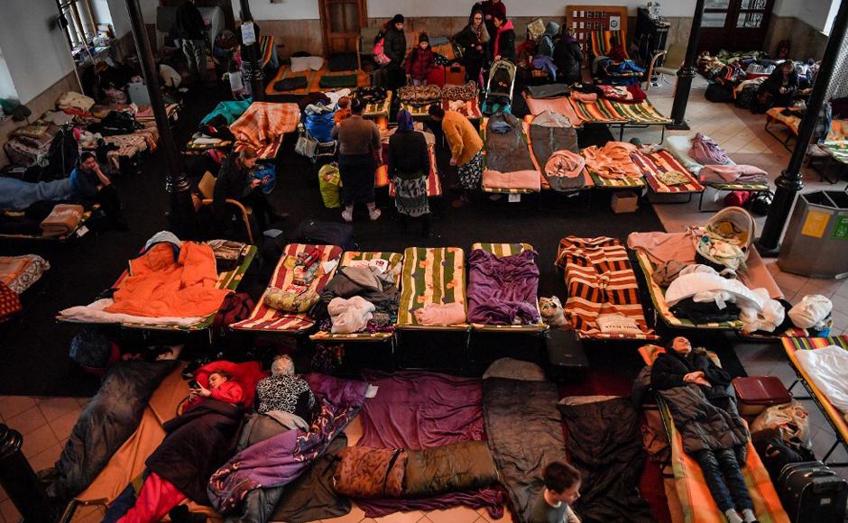 Ucranianos escansan en un refugio temporal en la estación principal de trenes de Cracovia, mientras esperan ser reubicados en otros alojamientos temporales en Polonia o en otro país.