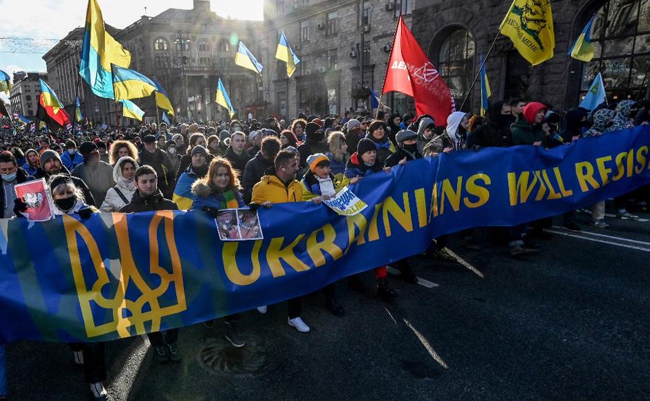 Los manifestantes gritan consignas mientras marchan detrás de una pancarta que dice “los ucranianos resistirán” con los colores de la Bandera Nacional durante una manifestación en Kiev, realizada para mostrar unidad en medio de las advertencias de Estados Unidos sobre una inminente invasión rusa.