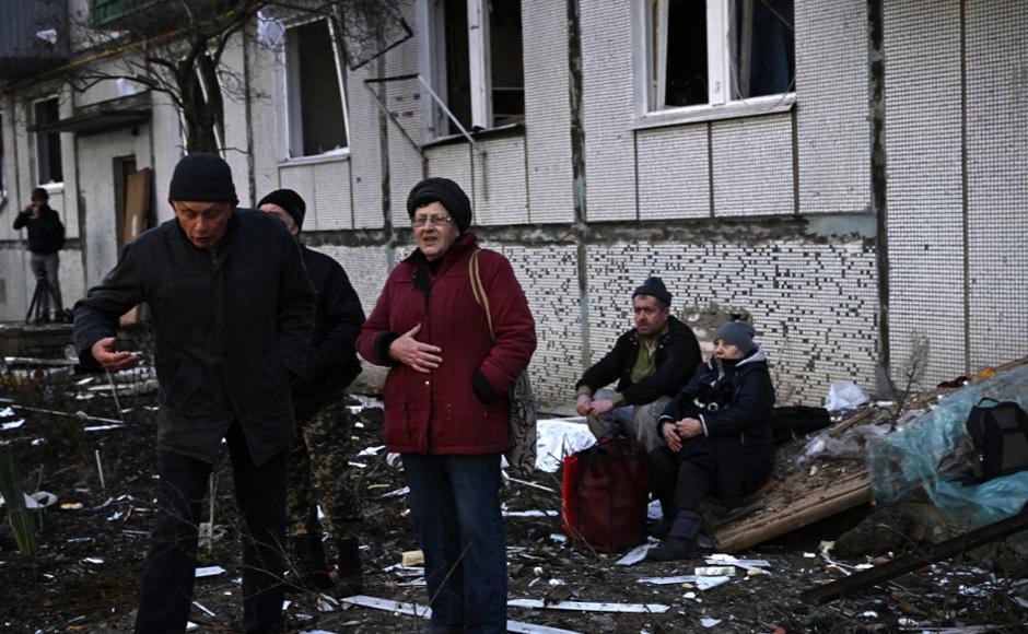 La gente se para fuera de un edificio destruido después de los bombardeos en la ciudad de Chuguiv, en el este de Ucrania.