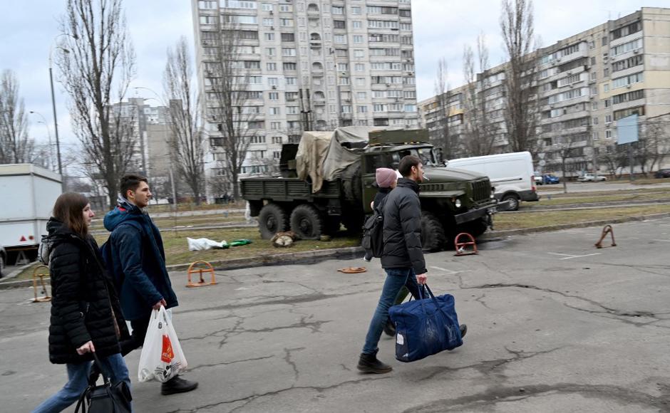 Los espectadores pasan junto a los cuerpos de militares rusos que vestían uniformes de servicio ucranianos que yacían al lado y dentro de un vehículo después de que les dispararan como parte de un grupo de asalto durante una escaramuza en la capital ucraniana de Kiev.