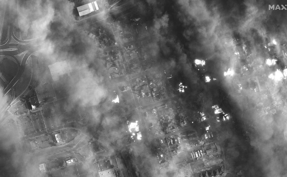 Esta imagen satelital WorldView-1 en blanco y negro publicada por Maxar Technologies muestra casas y centros comerciales envueltos en humo.