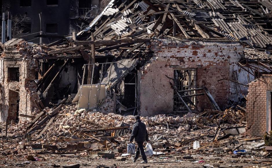 Un residente camina frente a un edificio destruido.