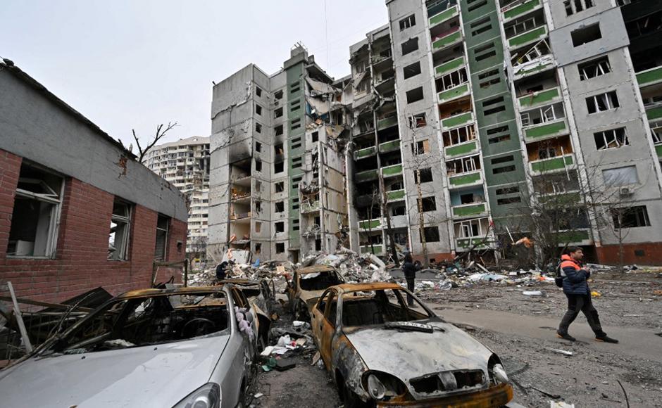 Un hombre pasa junto a autos destruidos y un edificio destruido en Chernigiv, en medio de la invasión rusa.