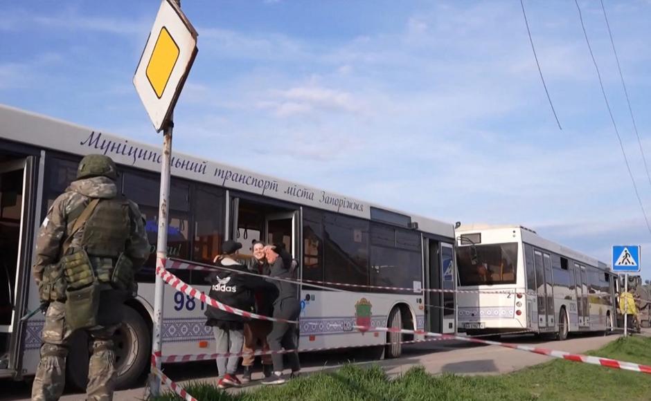 Personas abrazándose cerca de los autobuses de los civiles que son evacuados de un área cerca de la planta siderúrgica Azovstal en Mariúpol.