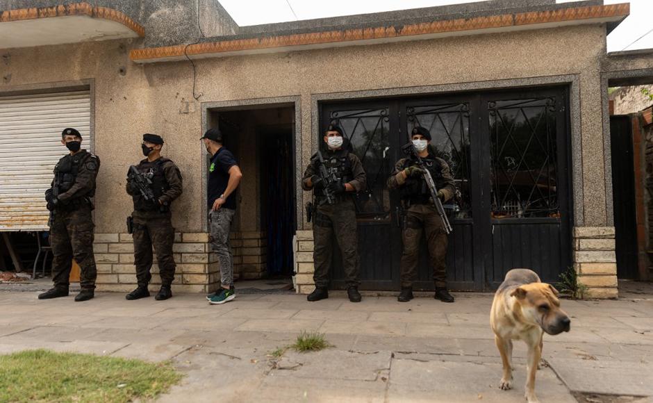 Oficiales hacen guardia afuera de la casa de Joaquín Aquino, también conocido como “El Paisa”, acusado de distribuir cocaína adulterada en José C. Paz, provincia de Buenos Aires, Argentina.