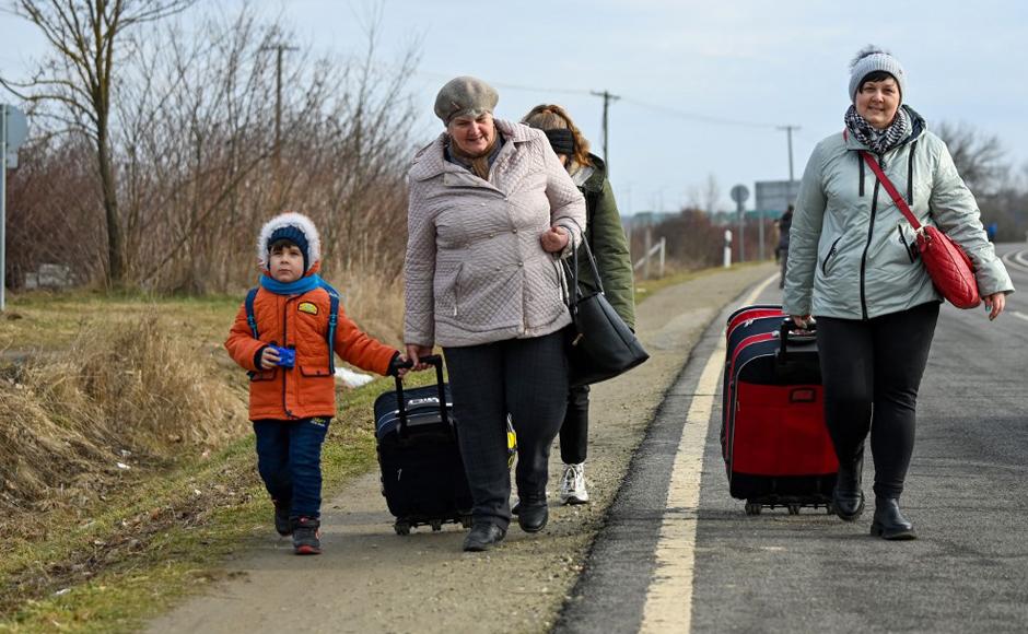 Ciudadanos ucranianos, entre ellos mujeres y niños que huyen del conflicto en su país, cruzan la frontera húngaro-ucraniana.