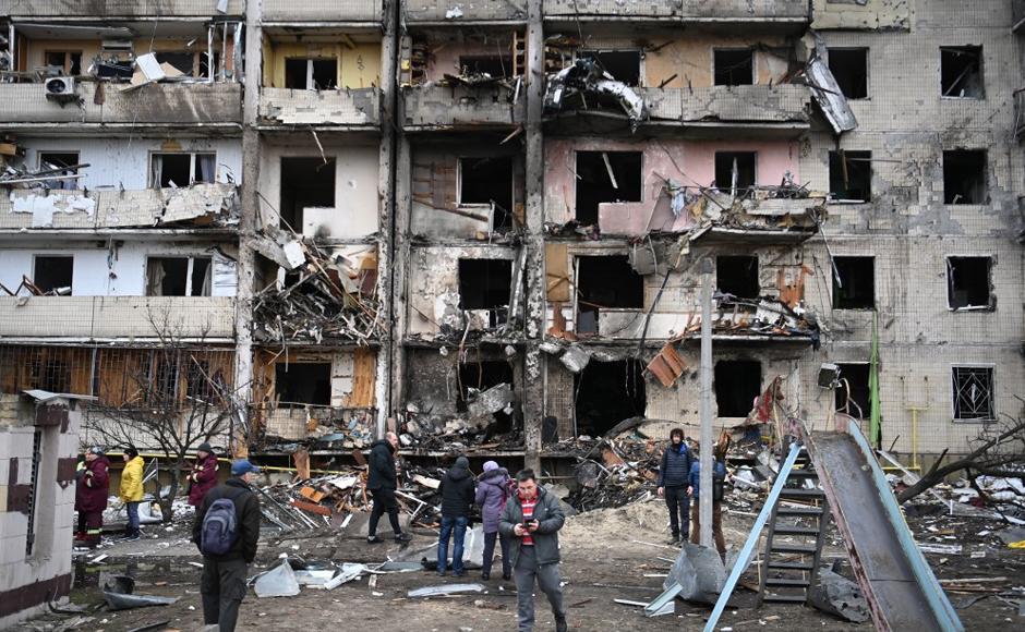 La gente se reúne frente a un edificio residencial dañado en la calle Koshytsa, un suburbio de la capital ucraniana, Kiev, donde supuestamente cayó un proyectil militar.