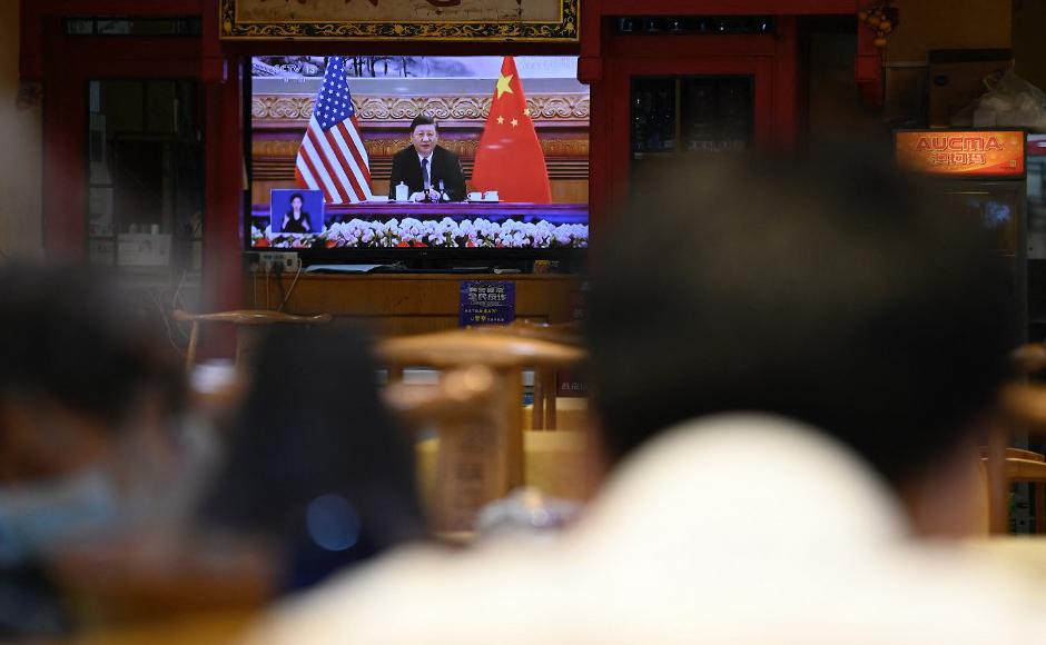 Una pantalla de televisión muestra un programa de noticias sobre una reunión virtual entre el presidente chino Xi Jinping y el presidente estadounidense Joe Biden.