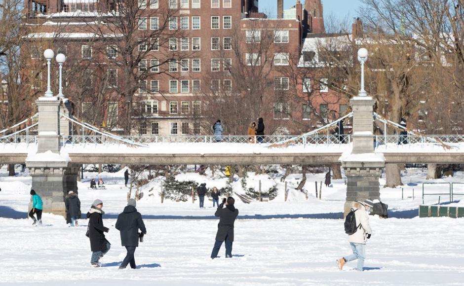 La gente camina en la laguna congelada y cubierta de nieve en Boston Common después de la tormenta de invierno Kenan.