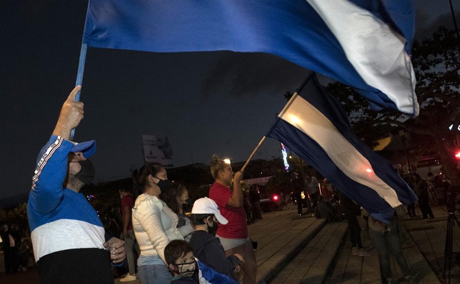 Exiliados nicaragüenses que viven en Costa Rica ondean banderas mientras participan en una vigilia contra el gobierno y el presidente Daniel Ortega.