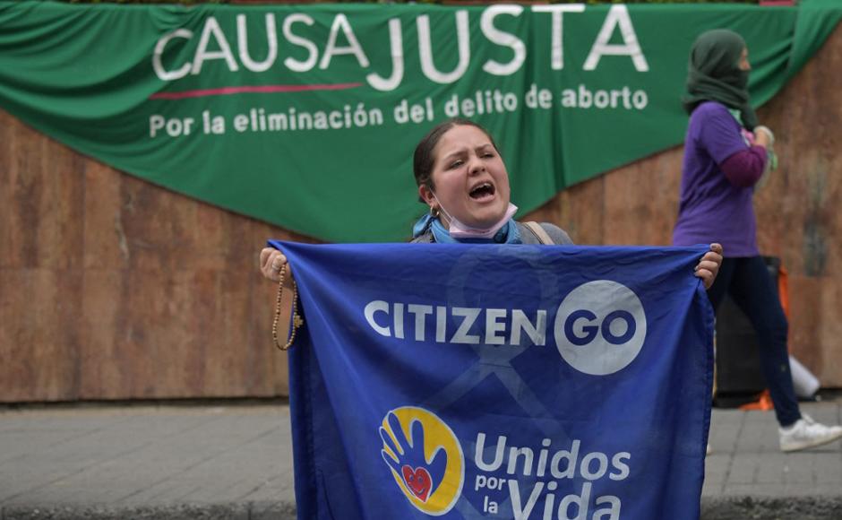 Una mujer se manifestaba en contra de la libertad del aborto frente a una pancarta a su favor mientras se esperaba que la Corte Constitucional se pronunciara sobre su despenalización.