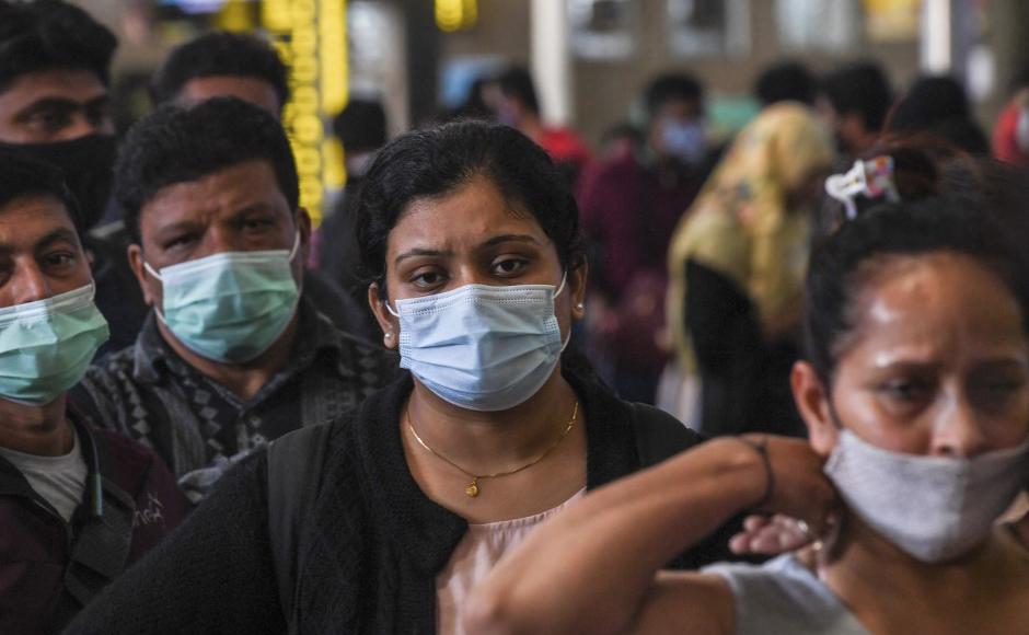 Pasajeros se paran a su llegada mientras el personal médico (no en la foto) toma una muestra para una prueba de reacción en cadena de la polimerasa.