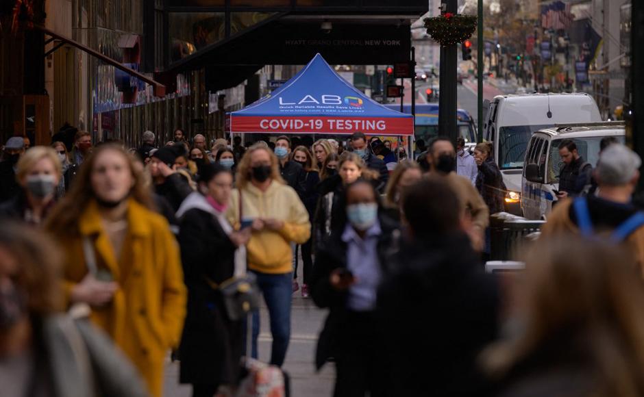 Personas hacen cola para hacerse la prueba de covid-19 en un puesto de pruebas al lado de la calle en Nueva York.