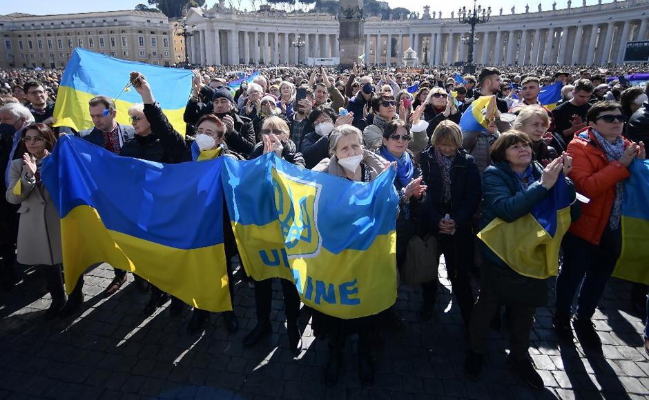 Los fieles sostienen banderas ucranianas mientras el papa Francisco pronuncia la oración dominical del Ángelus.