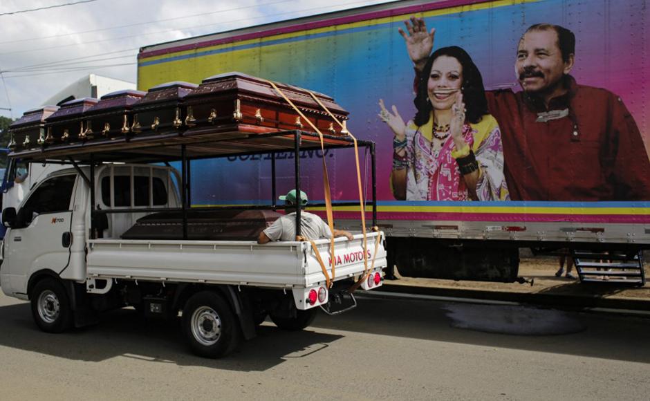 Un camión con ataúdes pasa junto a una pancarta del presidente de Nicaragua y candidato presidencial, Daniel Ortega y su esposa.