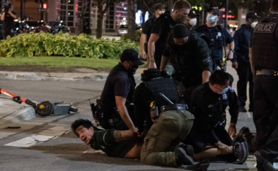 Un hombre es sometido contra el suelo por varios agentes policiales.