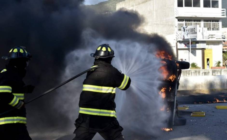 Los bomberos tratan de apagar un carro en llamas después que los estudiantes prendieran fuego al Palacio Municipal en Chilpancingo.