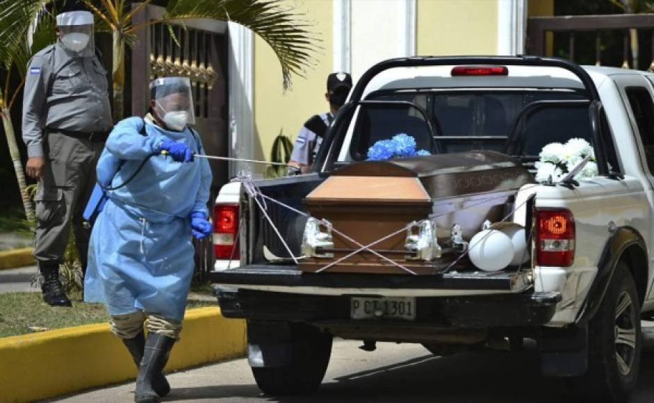 Un empleado del cementerio desinfecta el ataúd donde va el cuerpo del enfermero. Foto AFP