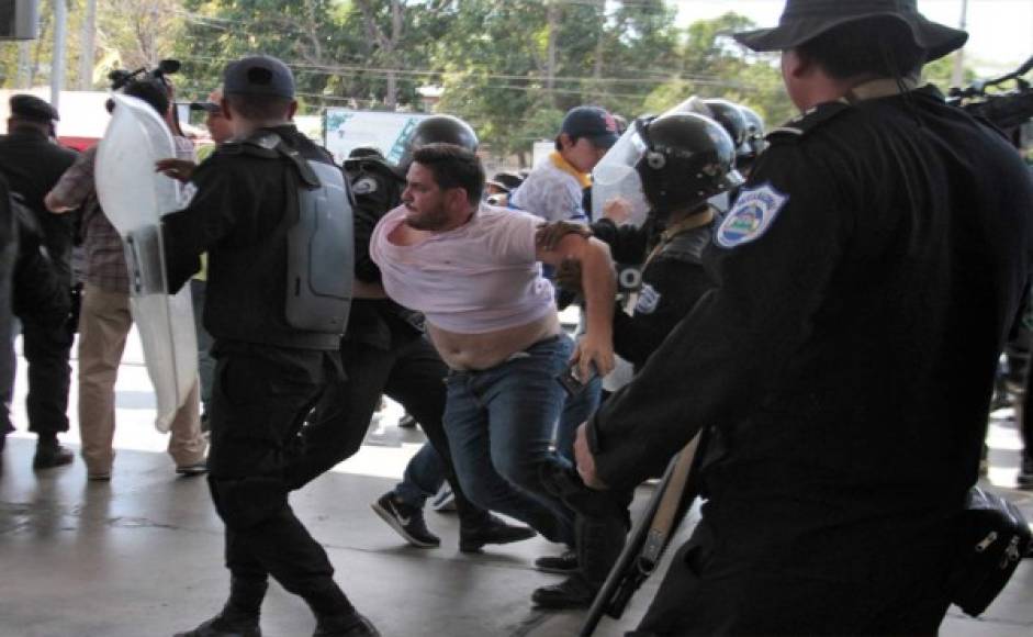 Oficiales de la policía antidisturbios de Nicaragua luchan con el camarógrafo de la AFP Luis Sequeira y sus colegas ante una protesta convocada por grupos de la oposición para exigir al gobierno la liberación de los arrestados por participar en protestas antigubernamentales en Managua.