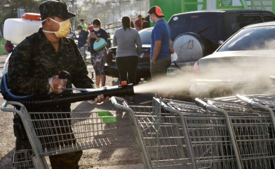 Un soldado de la guardia presidencial hondureña desinfecta los carros de compras afuera de un supermercado durante un descanso del toque de queda impuesto por el gobierno contra la propagación del nuevo coronavirus, en Tegucigalpa, el 19 de marzo de 2020.