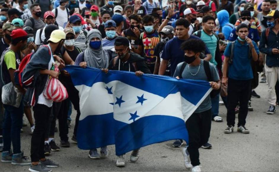 Los migrantes hondureños sostienen la Bandera Nacional después de romper una cerca policial y entrar a Guatemala desde Corinto. Foto AFP