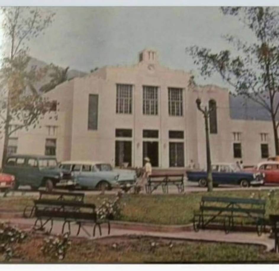 Luego de su remodelación, el Palacio Municipal de San Pedro Sula conservó por unos años el paso vehicular por el frente. Obsérverse el tipo de vehículos y las bancas en el parque central.