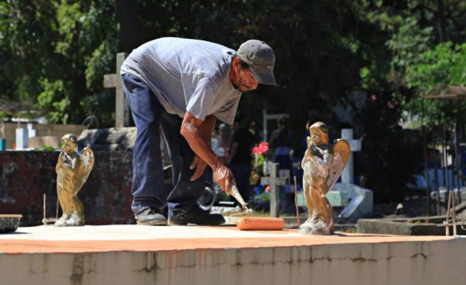 Pintar y restaurar las tumbas ayuda a muchos a ganarse unos cuantos lempiras en el cementerio La Puerta.