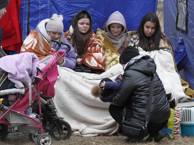 Refugiados ucranianos, cubiertos con mantas, se recuperan frente a una carpa después de pasar el cruce fronterizo rumano-ucraniano en Siret, en el norte de Rumania, el 27 de febrero de 2022.