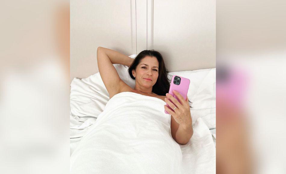 Mientras tanto, se puede ver una fotografía de Alessandra Rosado en la cama cubierta por sábanas blancas y sosteniendo su teléfono en la mano mientras sonríe a la cámara.