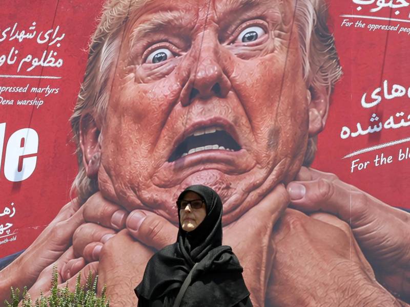 Una mujer pasa junto a una valla publicitaria antiestadounidense y anti-Trump en una calle de Teherán, Irán. EFE/EPA/ABEDIN TAHERKENAREH