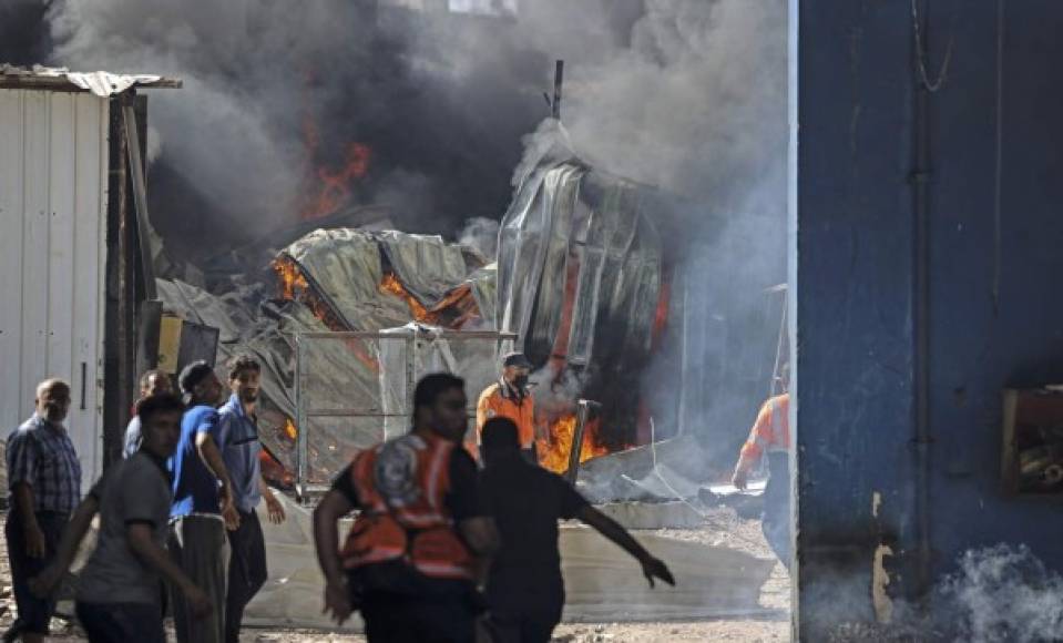 Los bomberos palestinos se apresuran a extinguir un enorme incendio en la fábrica de colchones Foamco al este de Jabalia en el norte de la Franja de Gaza, el 17 de mayo de 2021 (Foto de MAHMUD HAMS / AFP).