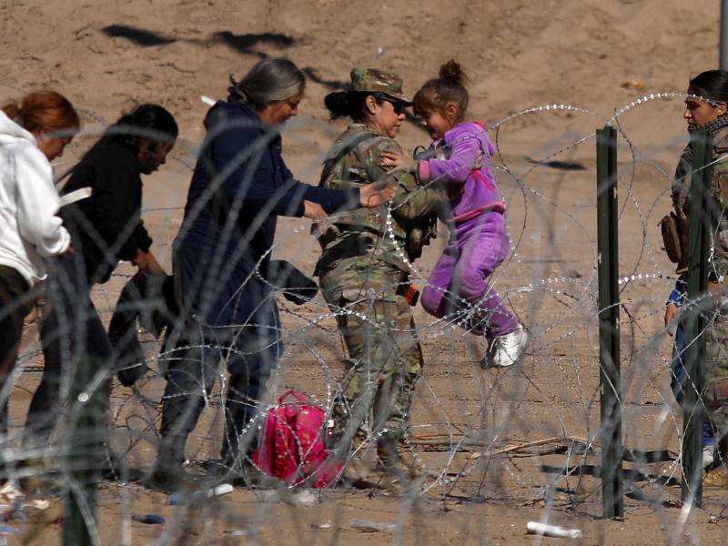 Un agente de la Guardia Nacional de Texas ayuda a una familia migrante atrapada en el alambre de la frontera.