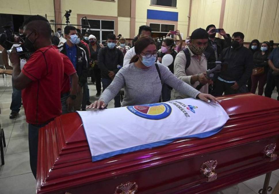 Una mujer coloca la bandera de la Facultad de Enfermería sobre el ataúd de la enfermera Keyla Martínez durante su funeral en La Esperanza. AFP