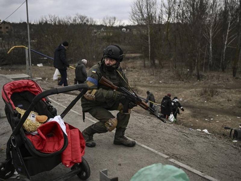 Un militar ucraniano se pone a cubierto mientras la gente evacúa la ciudad de Irpin.