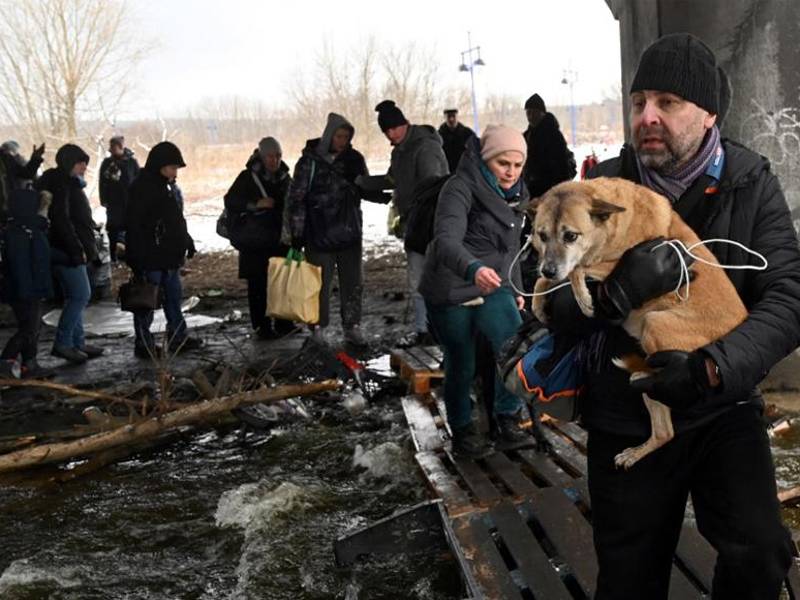 Un hombre carga un perro para cruzar un puente destruido mientras evacua la ciudad de Irpin, al noroeste de Kiev.