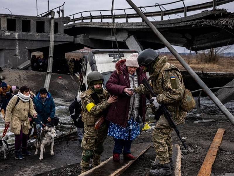 Soldados ucranianos ayudan a una anciana a cruzar un puente destruido mientras evacua la ciudad de Irpin, al noroeste de Kiev.