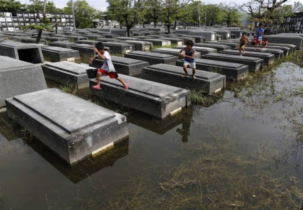 FILIPINAS. Juego entre las tumbas. Niños juegan en un cementerio inundado tras los recientes tifones, en el pueblo de Macabebe. Foto: EFE/Francis R. Malasig
