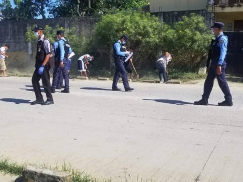 Los oficiales de la Policía Nacional observan a los ciudadanos realizando trabajo comunitario.
