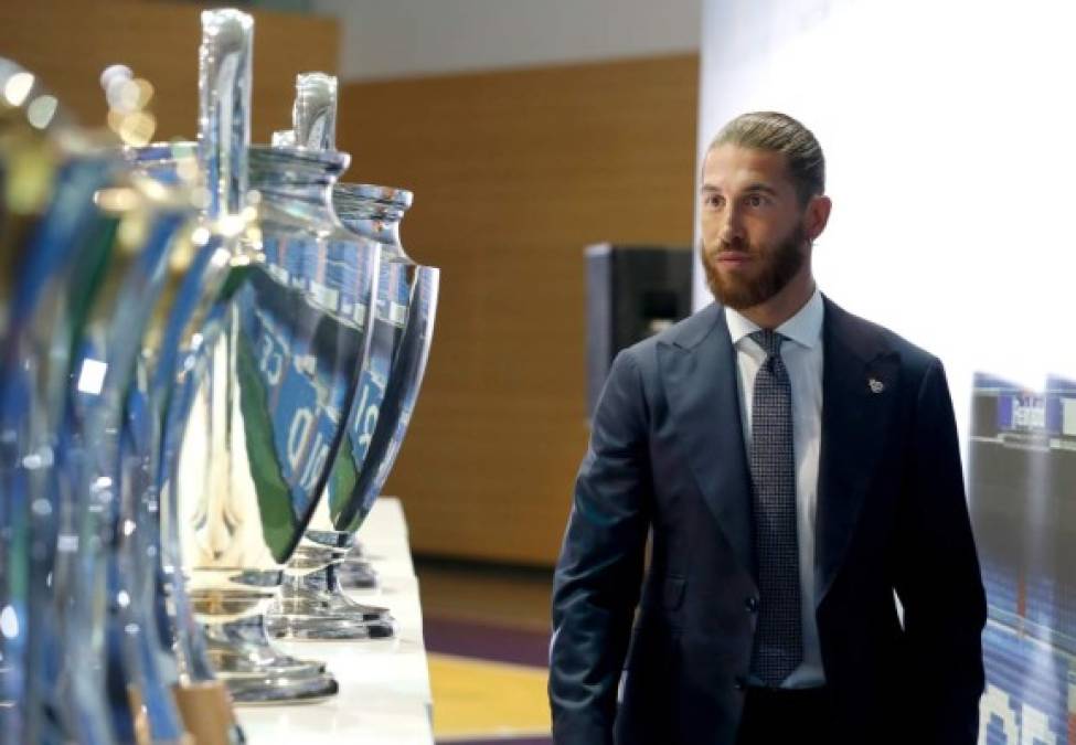 Sergio Ramos mira los trofeos de la 'Orejona' de la Champions que ha ganado en el Real Madrid.
