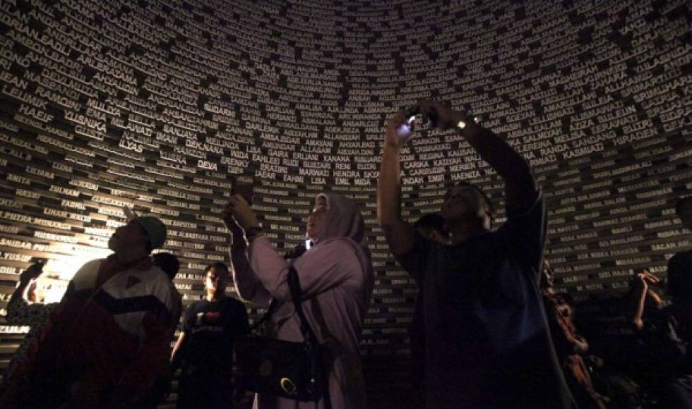 Varias personas fotografían los nombres de las víctimas del maremoto de 2004 en el Museo del Tsunami en Banda Aceh.