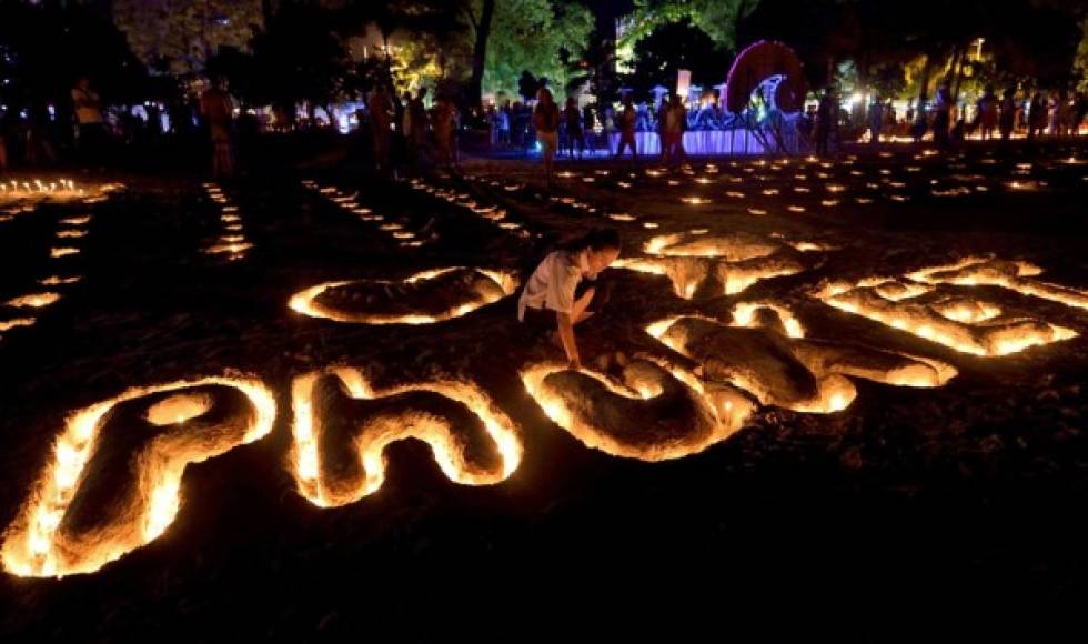 Una estudiante tailandés coloca velas en una escultura de arena durante las conmemoraciones del décimo aniversario del tsunami de 2004 en la playa de Patong, en la provincia de Phuket.