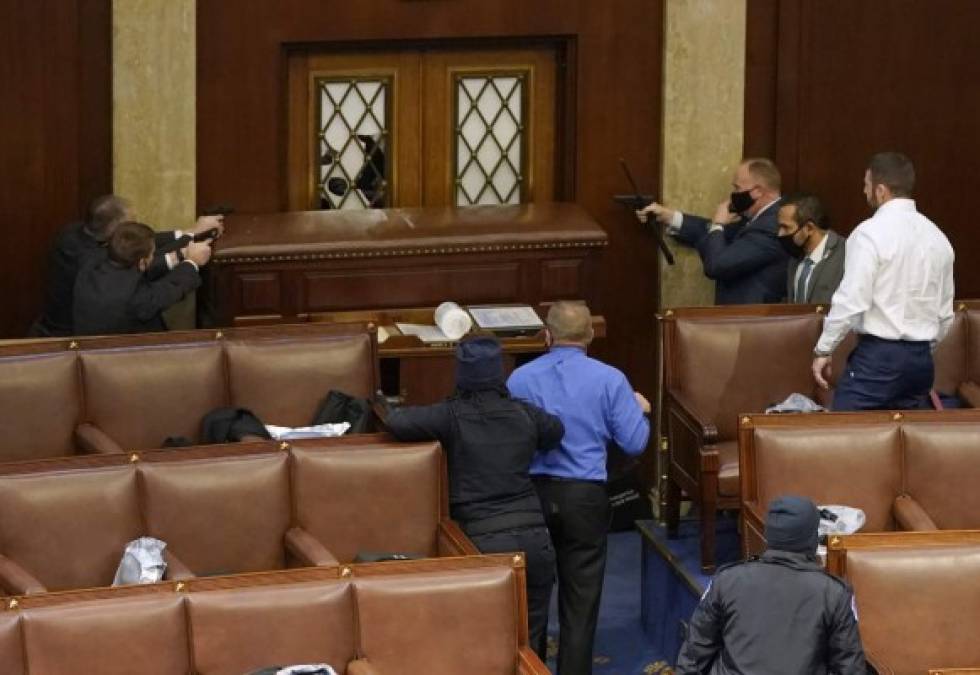 WASHINGTON, DC - JANUARY 06: U.S. Capitol police officers point their guns at a door that was vandalized in the House Chamber during a joint session of Congress on January 06, 2021 in Washington, DC. Congress held a joint session today to ratify President-elect Joe Biden's 306-232 Electoral College win over President Donald Trump. A group of Republican senators said they would reject the Electoral College votes of several states unless Congress appointed a commission to audit the election results. Drew Angerer/Getty Images/AFP1<br/><br/>== FOR NEWSPAPERS, INTERNET, TELCOS & TELEVISION USE ONLY ==<br/><br/>