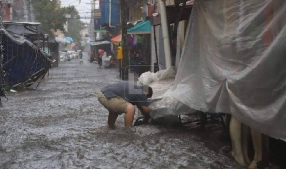 Un comerciante intenta resguardar sus pertenencias en un punto del centro de San Pedro Sula.