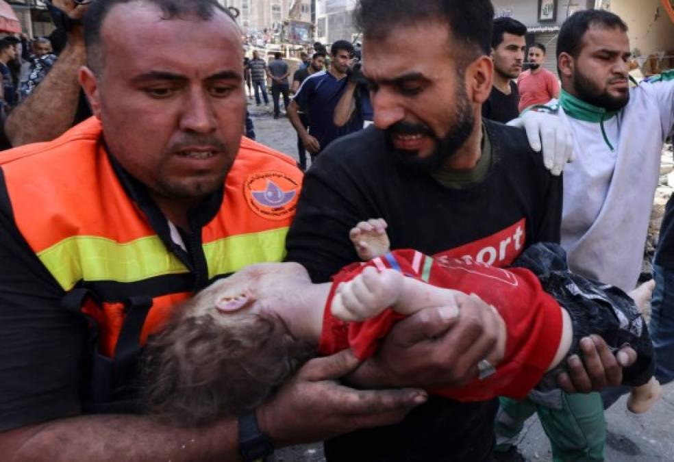 EDITORS NOTE: Graphic content / TOPSHOT - Palestinians recover the body of a child from the rubble of a destroyed building in Gaza City's Rimal residential district on May 16, 2021, following massive Israeli bombardment on the Hamas-controlled enclave. - Israel's army said it had bombed the home of the political leader of Islamist group Hamas in the Gaza Strip, as the UN Security Council was to meet amid global alarm about the escalating conflict. (Photo by MAHMUD HAMS / AFP)